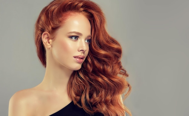 Mulher ruiva com olhar terno Belo modelo com penteado encaracolado longo e denso e maquiagem vívida