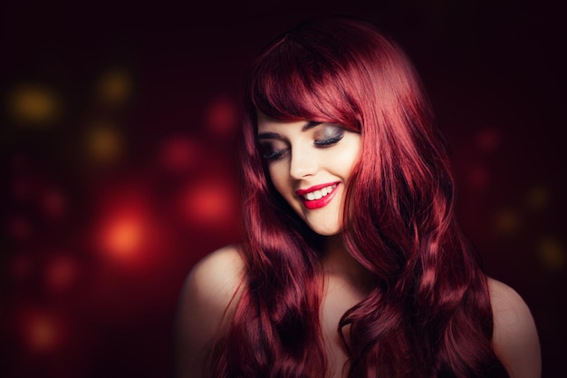 Mulher ruiva com penteado encaracolado longo vermelho Modelo de moda sorridente no fundo da festa glitter