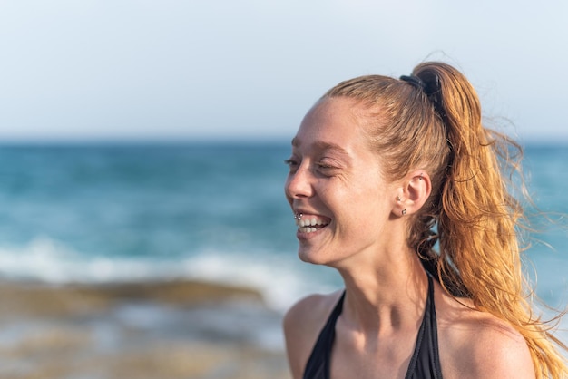 Mulher ruiva com rabo de cavalo na praia rindo