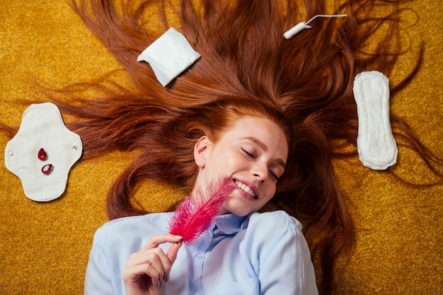 Mulher ruiva de cabelo comprido ruivo deitada no chão com juntas orgânicas ecológicas feitas de bio-algodão e escolha de tampão descartável.