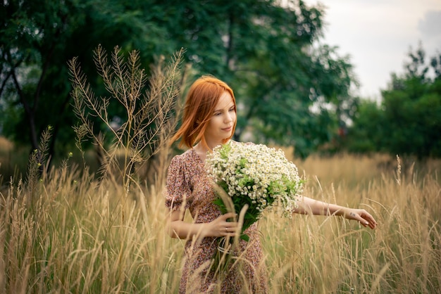 Mulher ruiva de quarenta anos com um grande buquê de flores silvestres no verão na natureza