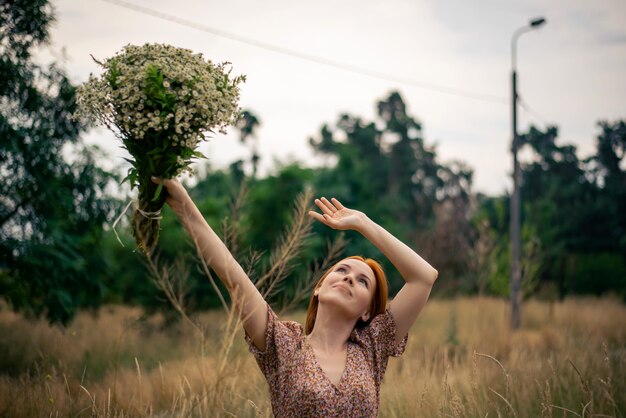 Mulher ruiva de quarenta anos com um grande buquê de flores silvestres no verão na natureza