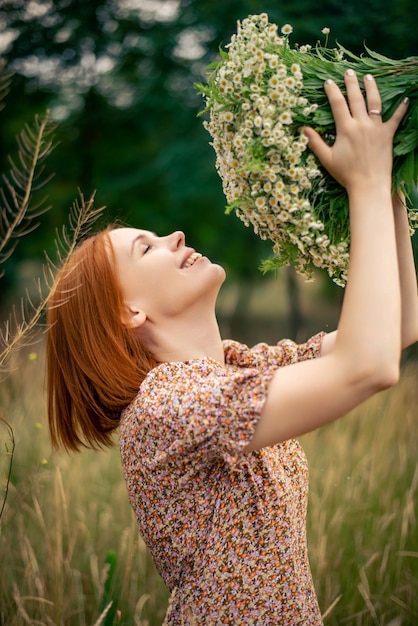 Mulher ruiva de quarenta anos com um grande buquê de flores silvestres no verão na natureza