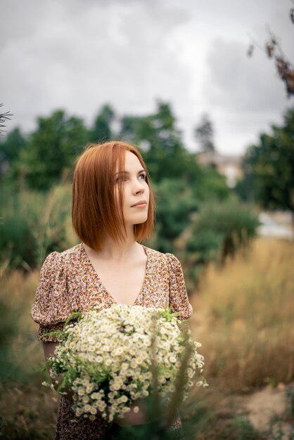 Mulher ruiva de quarenta anos com um grande buquê de flores silvestres no verão na natureza