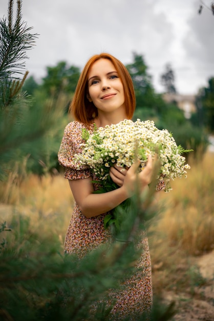 Mulher ruiva de quarenta anos com um grande buquê de flores silvestres no verão na natureza