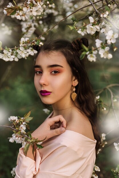 Mulher ruiva do retrato da beleza na primavera nos galhos de uma macieira