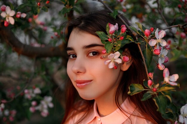 Mulher ruiva do retrato da beleza na primavera nos galhos de uma macieira