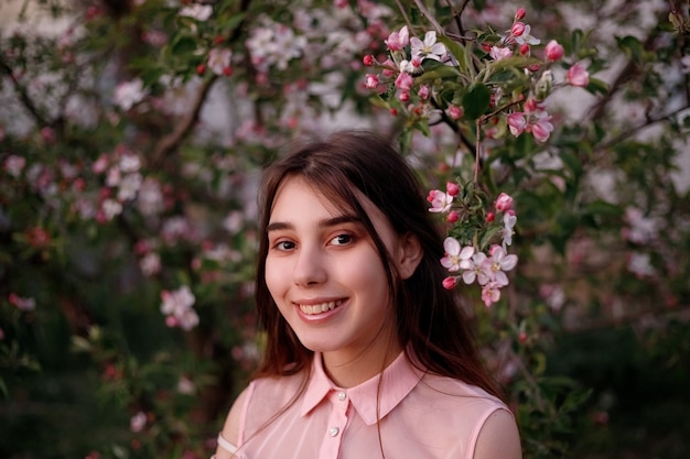 Mulher ruiva do retrato da beleza na primavera nos galhos de uma macieira