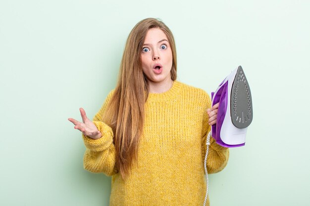 Mulher ruiva espantada, chocada e atônita com uma surpresa inacreditável. conceito de roupas de ferro