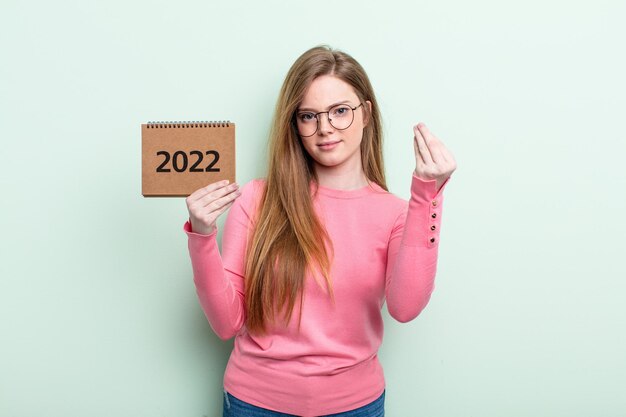 mulher ruiva fazendo gesto capice ou dinheiro, dizendo para você pagar o conceito de agenda 2022