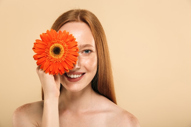 Mulher ruiva feliz segurando flor.