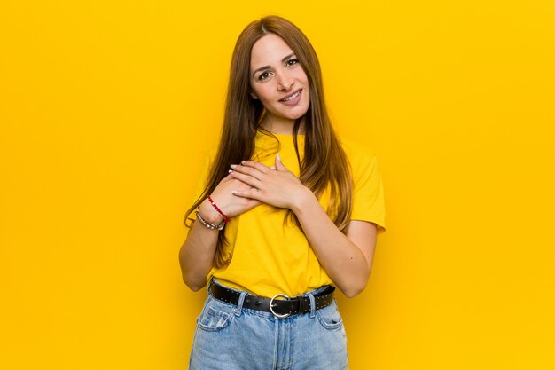 Mulher ruiva jovem gengibre tem expressão amigável, pressionando a palma da mão no peito. conceito de amor