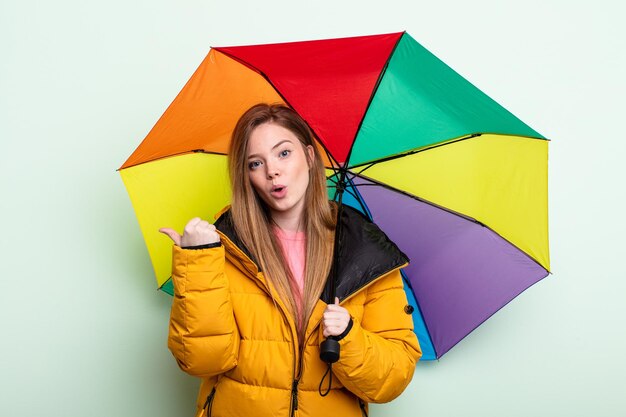 Mulher ruiva olhando atônita no conceito de guarda-chuva de descrença