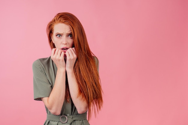 Mulher ruiva ruiva em vestido de seda de algodão verde em estúdio rosa com sensação de surpresa