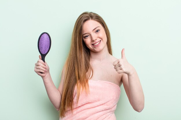 Mulher ruiva se sentindo orgulhosa, sorrindo positivamente com os polegares para cima. conceito de pente de cabelo