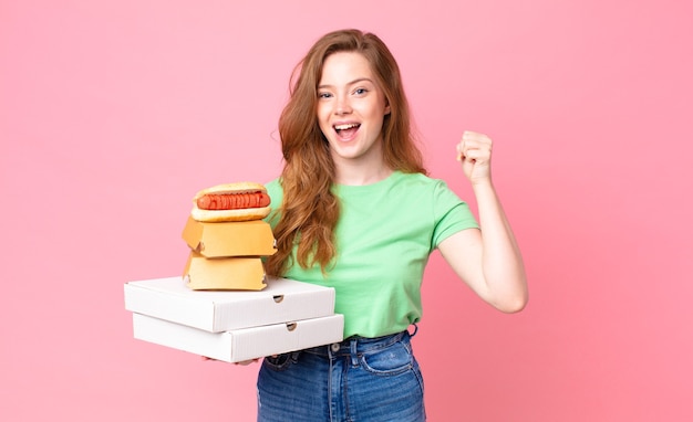 Mulher ruiva segurando caixas de fast food para levar