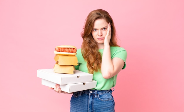 Mulher ruiva segurando caixas de fast food para levar