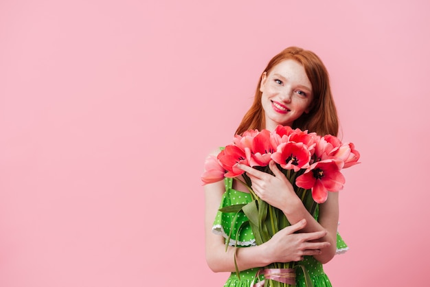 Mulher ruiva sorridente segurando o buquê de flores