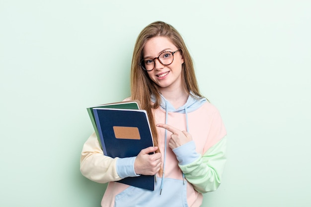 Mulher ruiva sorrindo alegremente, sentindo-se feliz e apontando para o lado. conceito de estudante