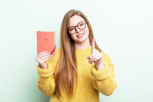 Mulher ruiva sorrindo com orgulho e confiança fazendo o conceito de planejador número um