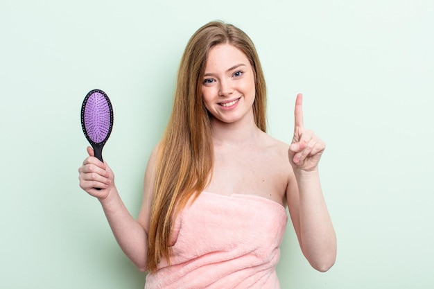 Mulher ruiva sorrindo e parecendo amigável, mostrando o número um. conceito de pente de cabelo