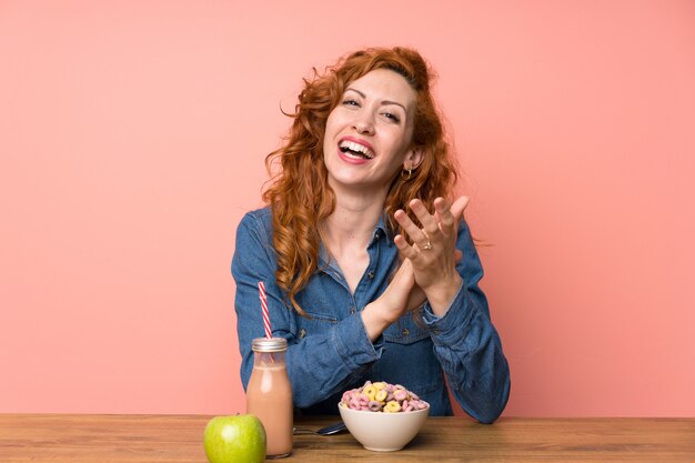 Mulher ruiva tomando cereais e frutas aplaudindo