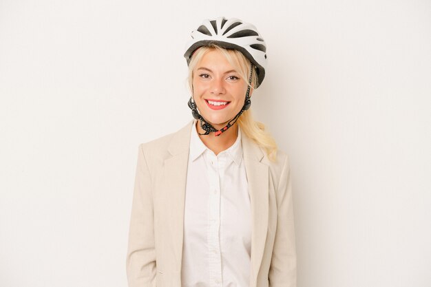 Mulher russa de negócios jovem segurando o capacete da bicicleta isolado no fundo branco feliz, sorridente e alegre.