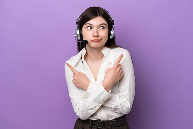 Mulher russa de telemarketing trabalhando com um fone de ouvido isolado em fundo roxo apontando para as laterais com dúvidas