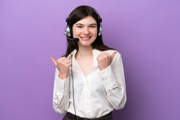 Mulher russa de telemarketing trabalhando com um fone de ouvido isolado em fundo roxo com polegares para cima gesto e sorrindo