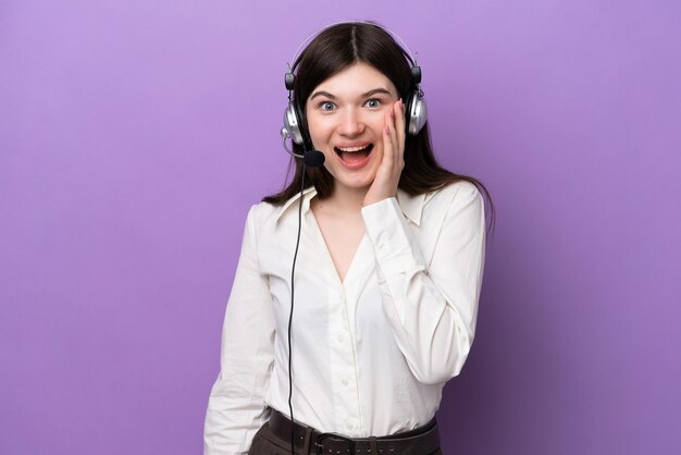 Mulher russa de telemarketing trabalhando com um fone de ouvido isolado em fundo roxo com surpresa e expressão facial chocada