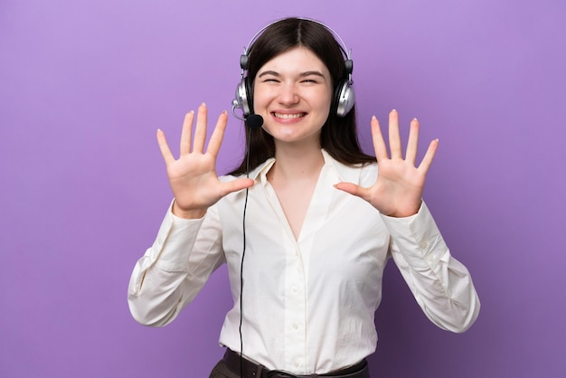 Mulher russa de telemarketing trabalhando com um fone de ouvido isolado em fundo roxo contando dez com os dedos