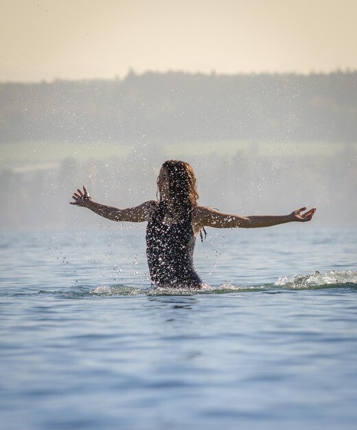 Foto mulher salpicando água no lago contra o céu