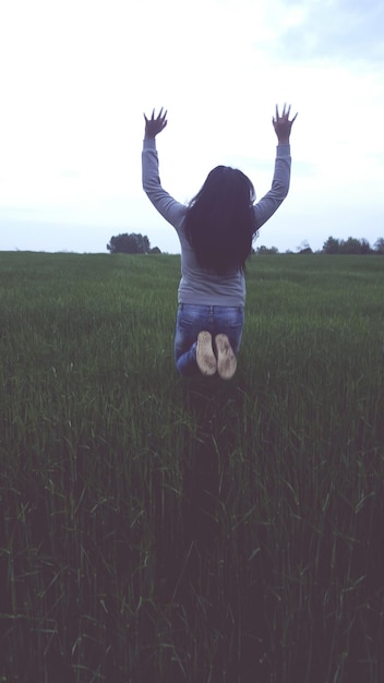 Foto mulher saltando sobre o campo contra o céu