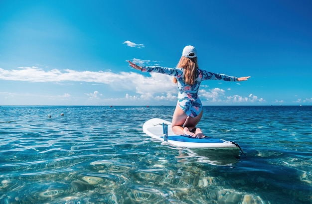 Mulher saudável e feliz em biquíni relaxando em uma prancha de surfe flutuando no mar azul-turquesa