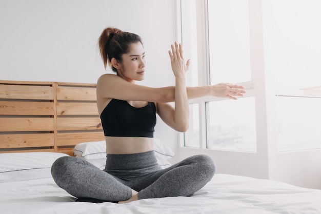 Mulher se alongando e se acalmando após o treino no quarto do apartamento dela