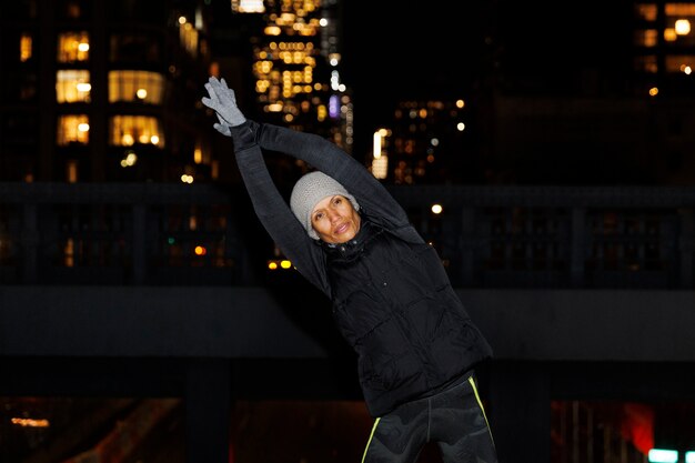 Foto mulher se alongando e se exercitando à noite na cidade
