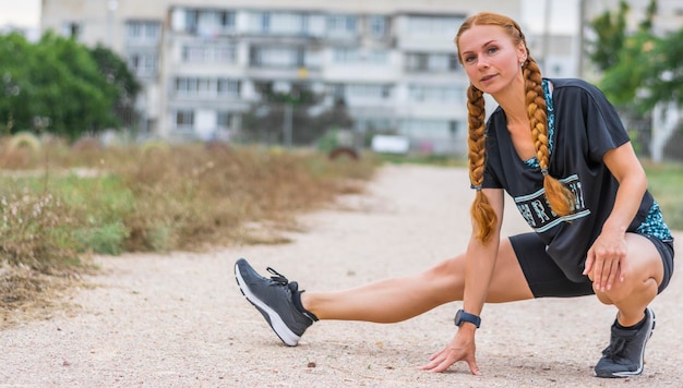 Mulher se alongando para fortalecer as pernas e desenvolver a preparação da flexibilidade das pernas para treinamento