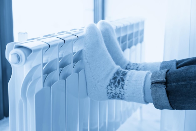 Mulher se aquecendo com os pés no aquecedor usando meias de lã