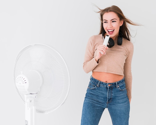 Foto mulher se divertindo cantando em um controle remoto