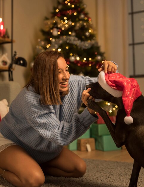 Mulher se divertindo no Natal com o cachorro dela usando chapéu de Papai Noel