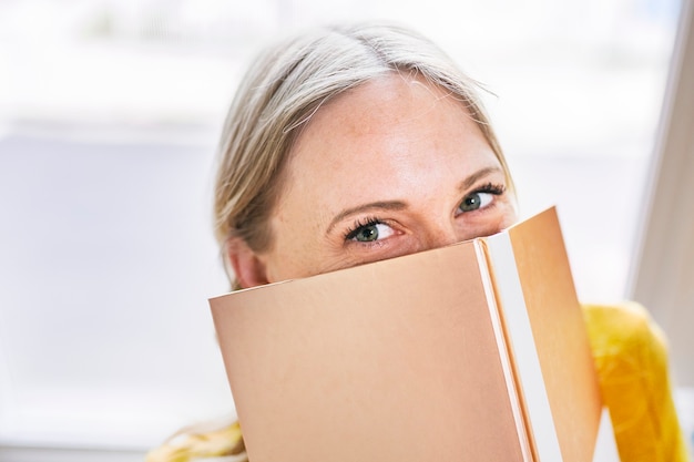 Mulher se escondendo atrás de um caderno de ouro brilhante