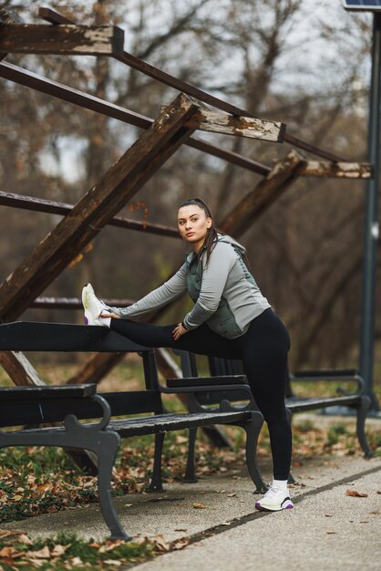 Foto mulher se estendendo em um banco no parque