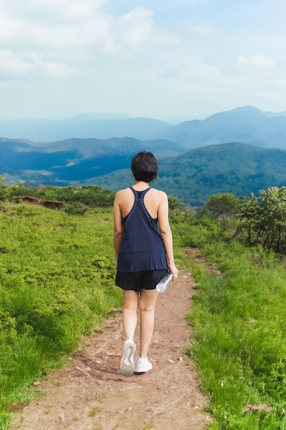 Mulher se exercitando andando em uma trilha de encosta com vista para a montanha