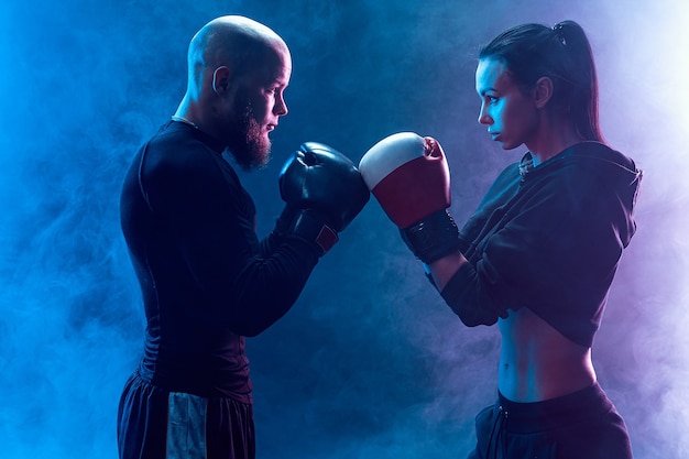 Mulher se exercitando com o treinador na aula de boxe e defesa pessoal