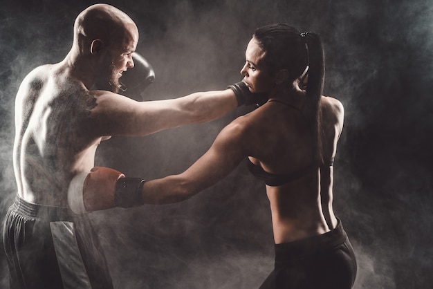 Mulher se exercitando com o treinador na aula de boxe e defesa pessoal