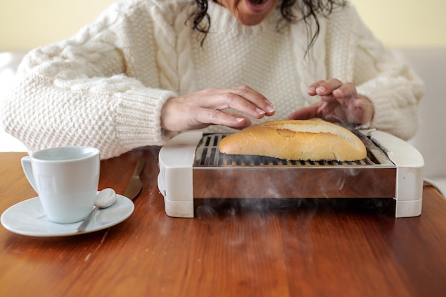 Mulher se le quema la rebanada de pan en la tostadora