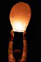 Foto mulher se preparando para lançar uma lanterna voadora cena noturna