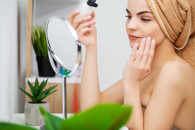 Mulher se preparando para o trabalho fazendo maquiagem de manhã no espelho do banheiro em casa