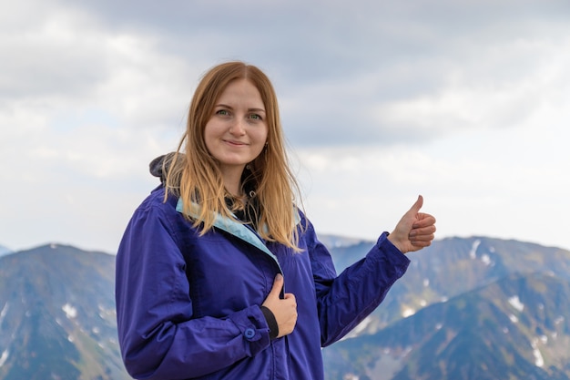 Mulher se sentindo feliz fazendo um polegar para cima com as mãos contra na paisagem de rochas da montanha