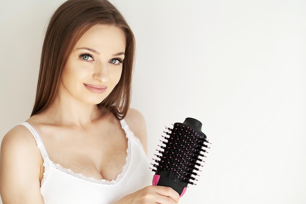 Mulher secando o cabelo com secador de cabelo e escova redonda